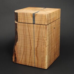 Puristisch und ursprünglich gestaltete Urne in Quaderform und sägerauer Oberfläche. Massivholzurne aus Kirschbaum.