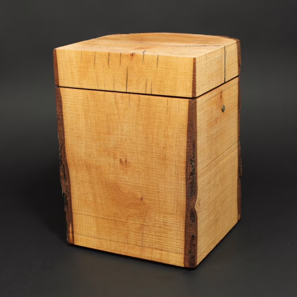 Puristisch gestaltete Holzurne aus Erle in Quaderform mit Waldkanten und sägerauer Oberfläche, ursprüngliche Naturholzstruktur